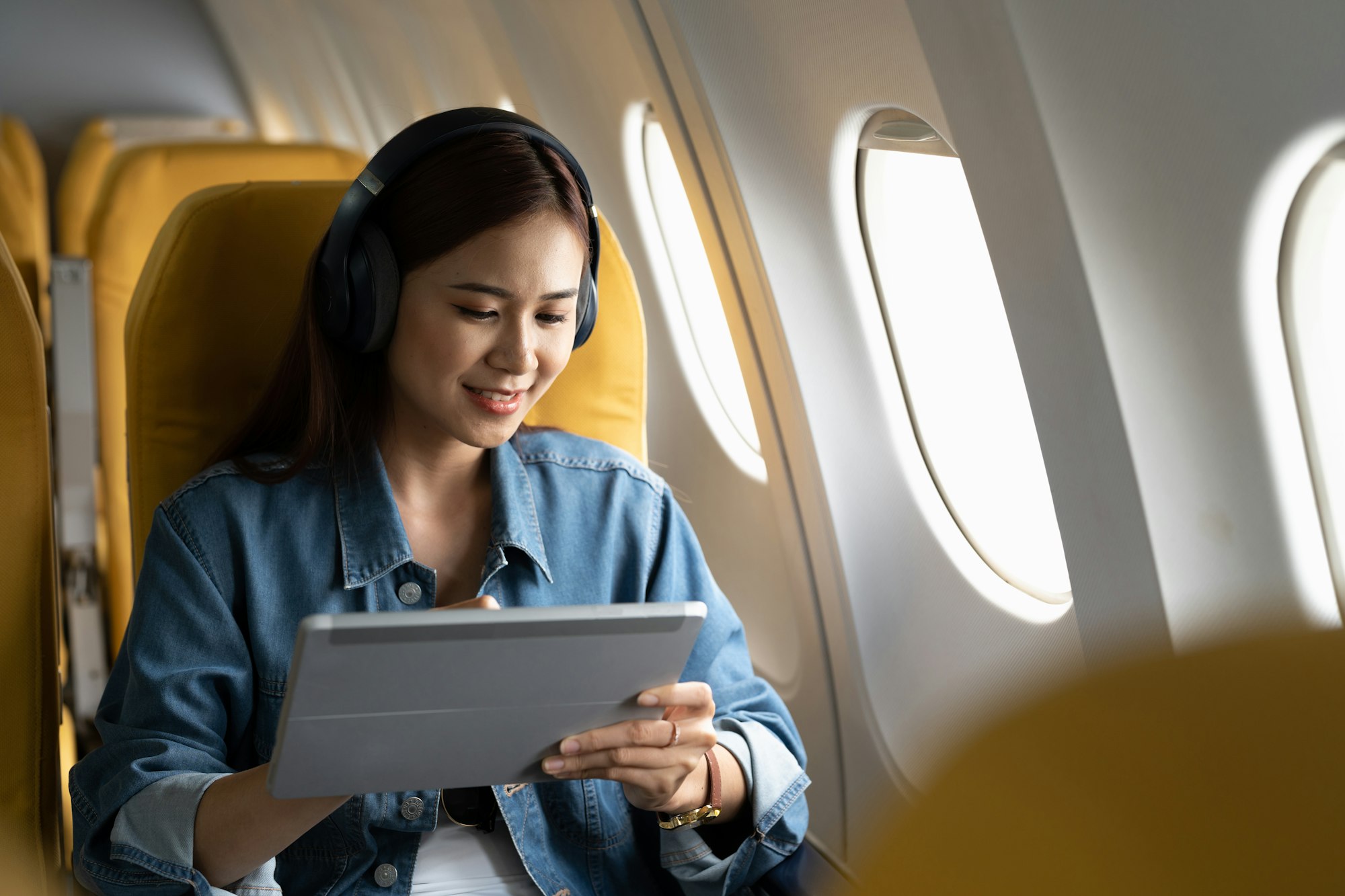 Beautiful asian travel woman watching movie on digital tablet in airplane